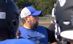 A Petrides football coach crunching numbers with his team on the field.