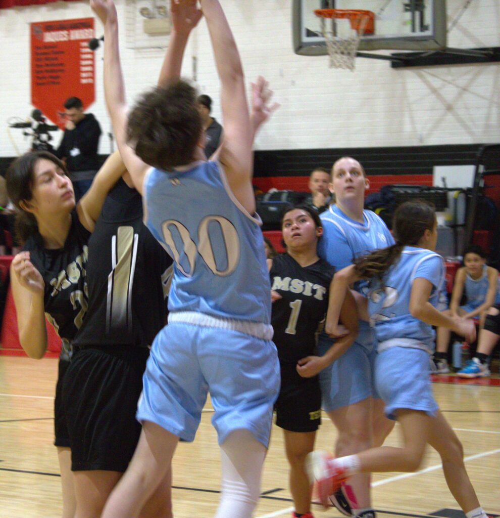 A group of girls playing basketball on a court in the first round of the Borough President's Cup.