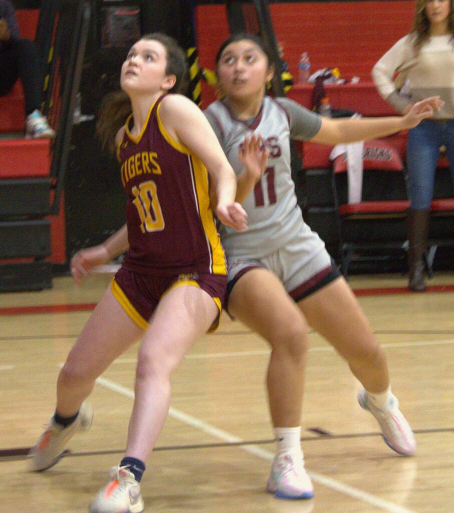 Two girls competing in the first round of the Borough President's Cup basketball tournament on a court.