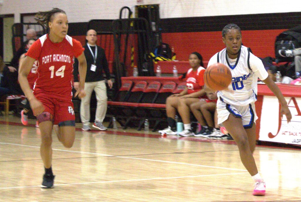 Two girls competing in the first round of the Borough President's Cup basketball tournament on a court.