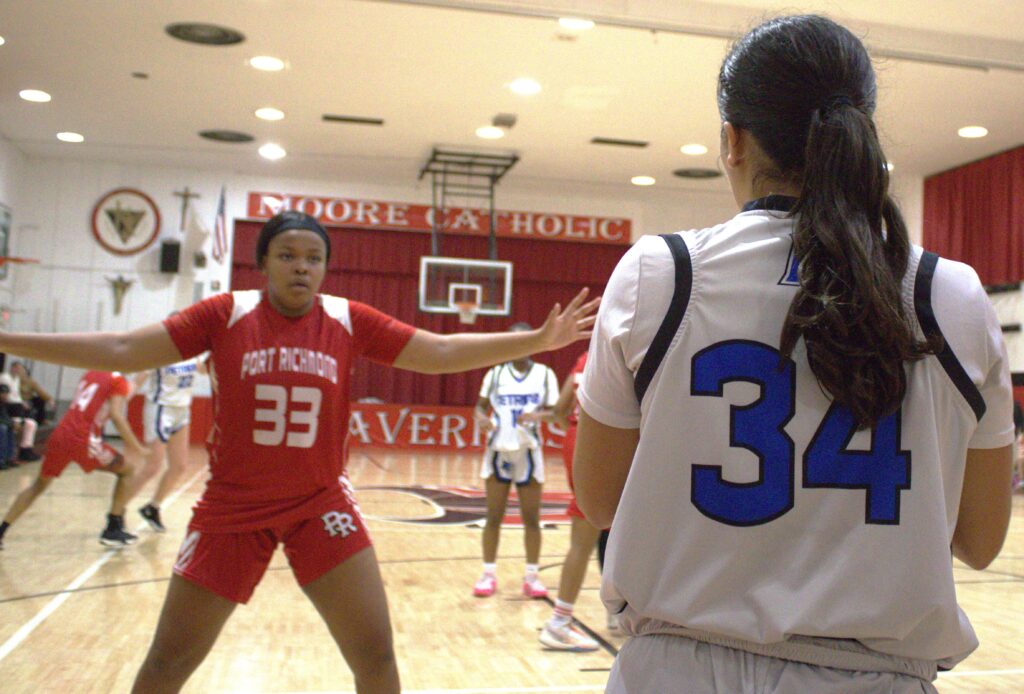 Two girls participating in the first round of the Borough President's Cup basketball tournament in a gym.