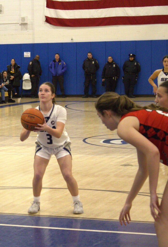 A group of girls playing basketball on the S.I. High School court during the Borough President's Tournament championship, showcasing their skills in the Sea Hill neighborhood.