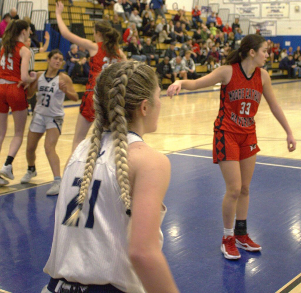 A group of girls playing basketball on a court during a tournament.