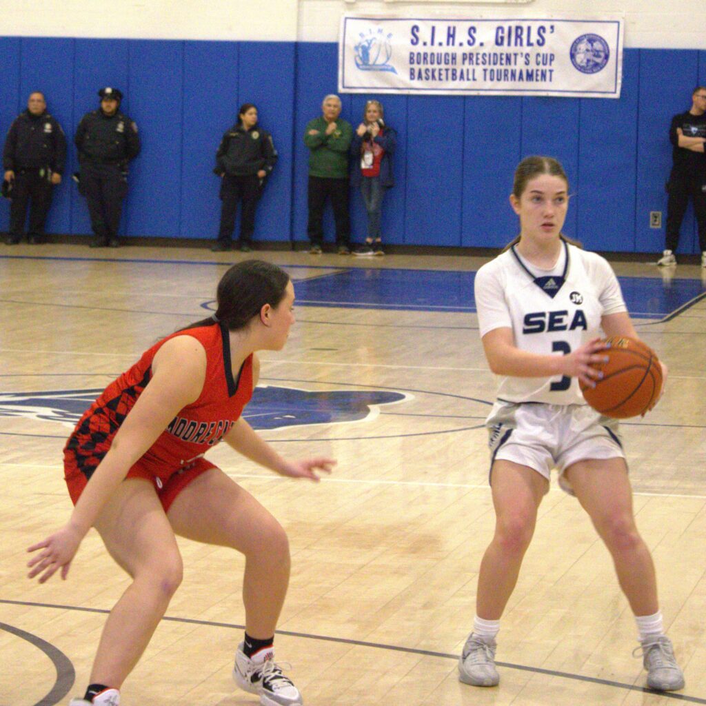 Two girls participating in the S.I. High School Girls' Borough President's Tournament, playing basketball on a court at Hillside Seashore.