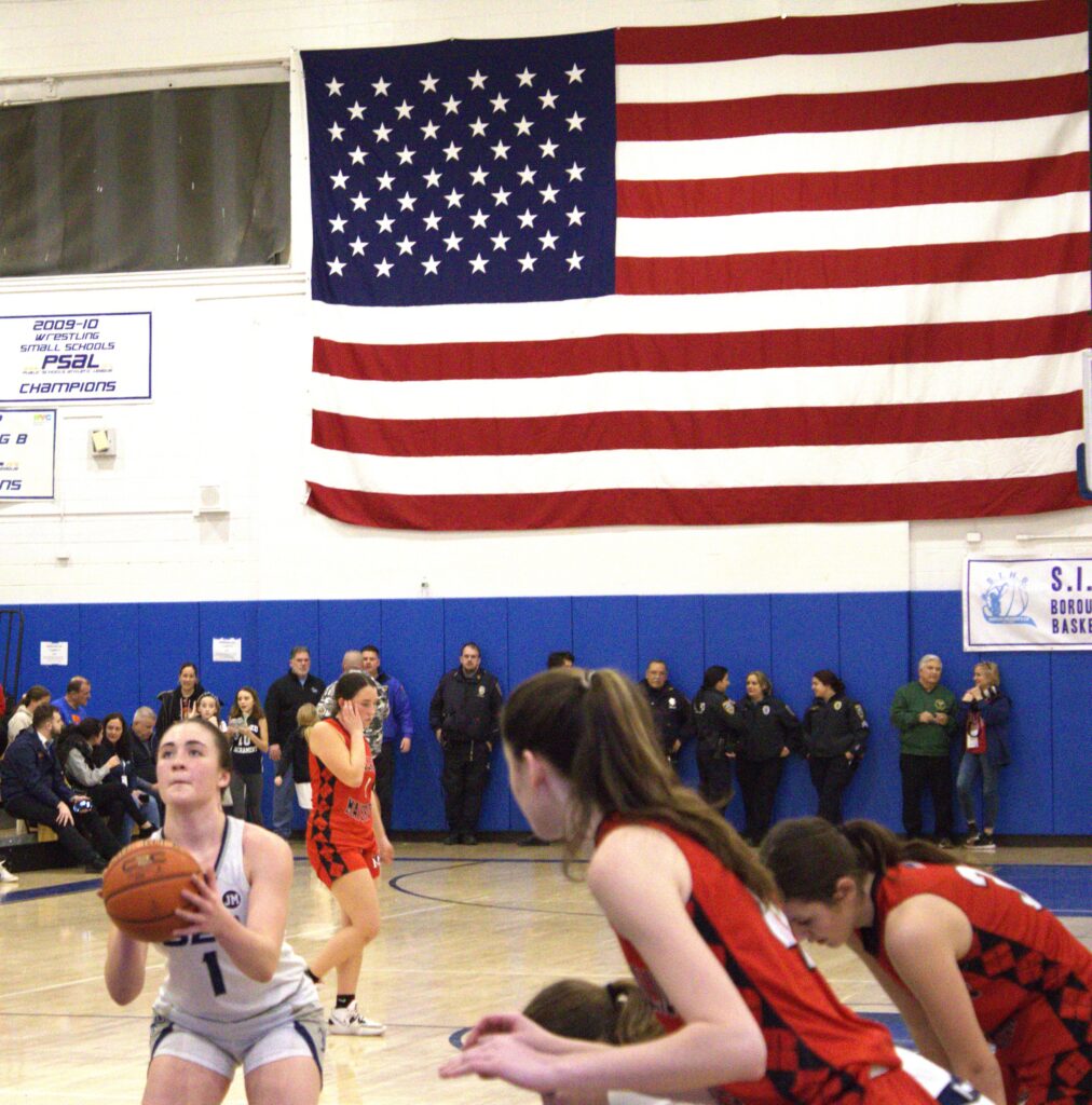 A group of girls playing basketball in a gym during the Girls' Borough President's Tournament.