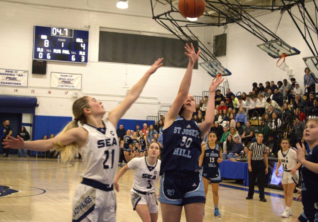 A group of girls participating in the Borough President's Cup Tournament, playing basketball in a gym by the sea.