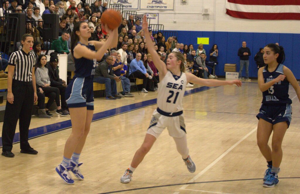 A girl is participating in the Borough President's Cup Tournament, attempting to block a basketball.