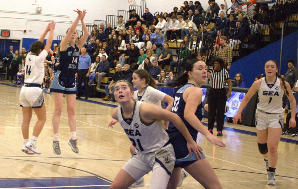 A group of girls participating in the Borough President's Cup Tournament and playing basketball on a court.