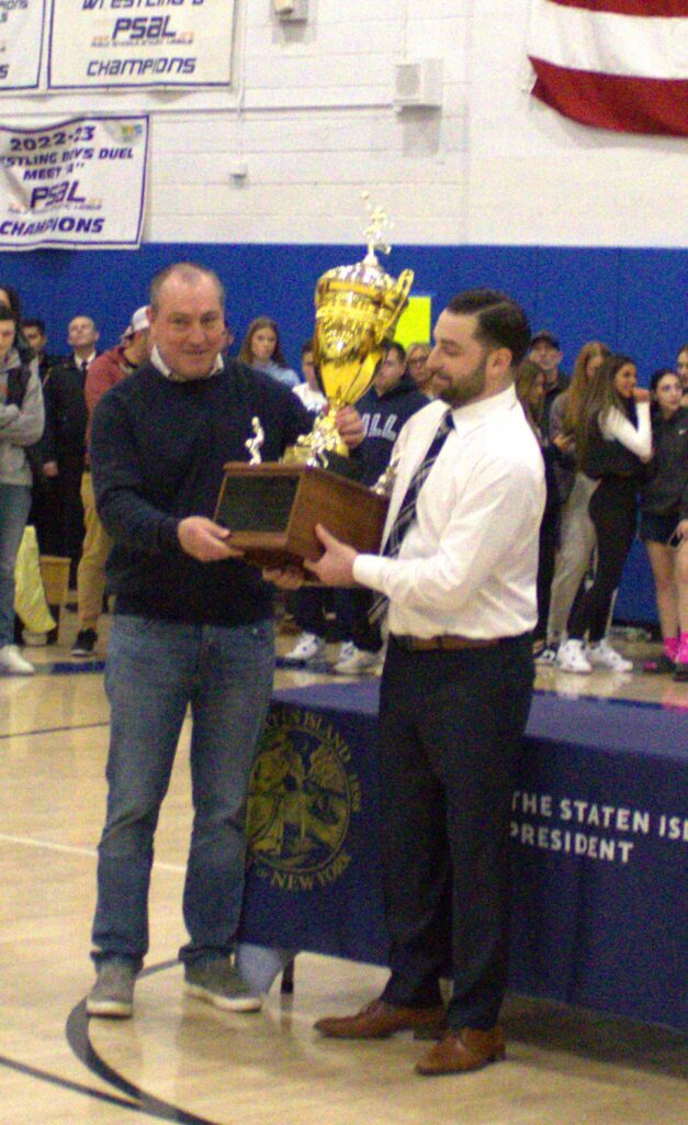 A man proudly holding the Borough President's Cup Tournament trophy.