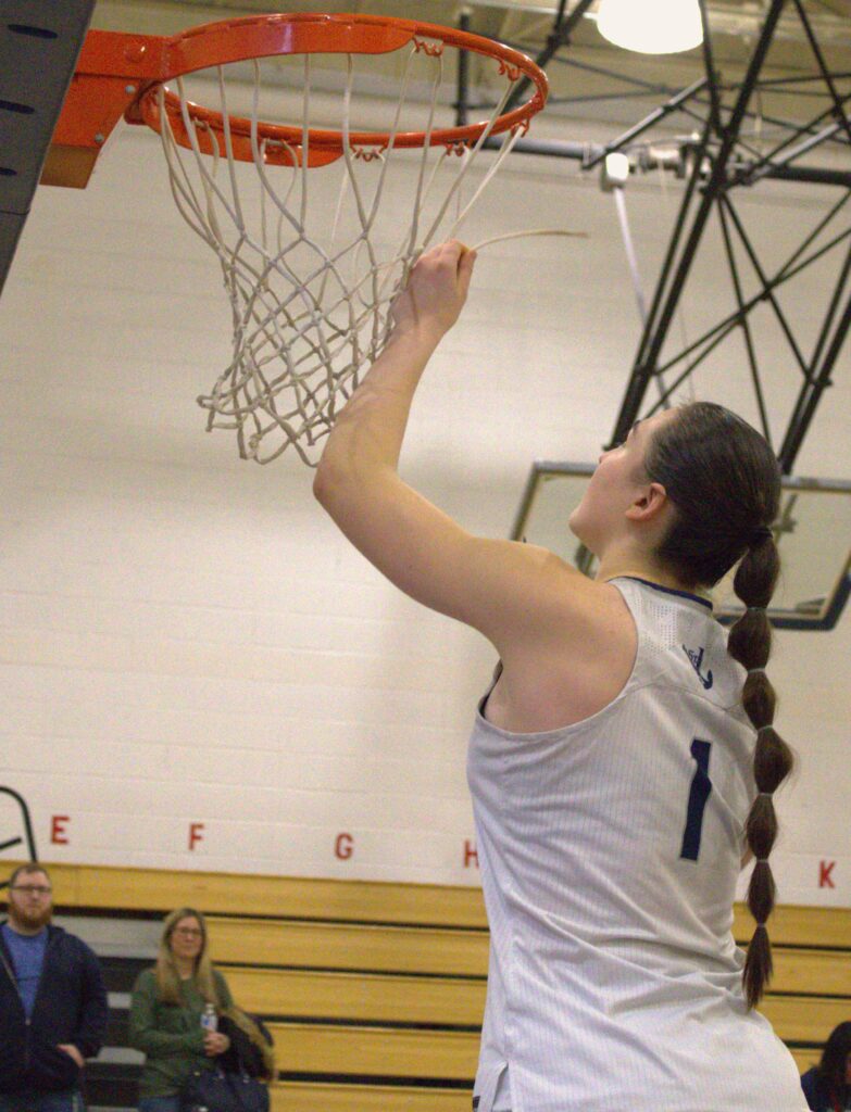 A woman participating in the Borough President's Cup Tournament, gracefully dunking a basketball hoop.