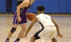 Two young men playing basketball on a court during the SIHSL Tournament championship.