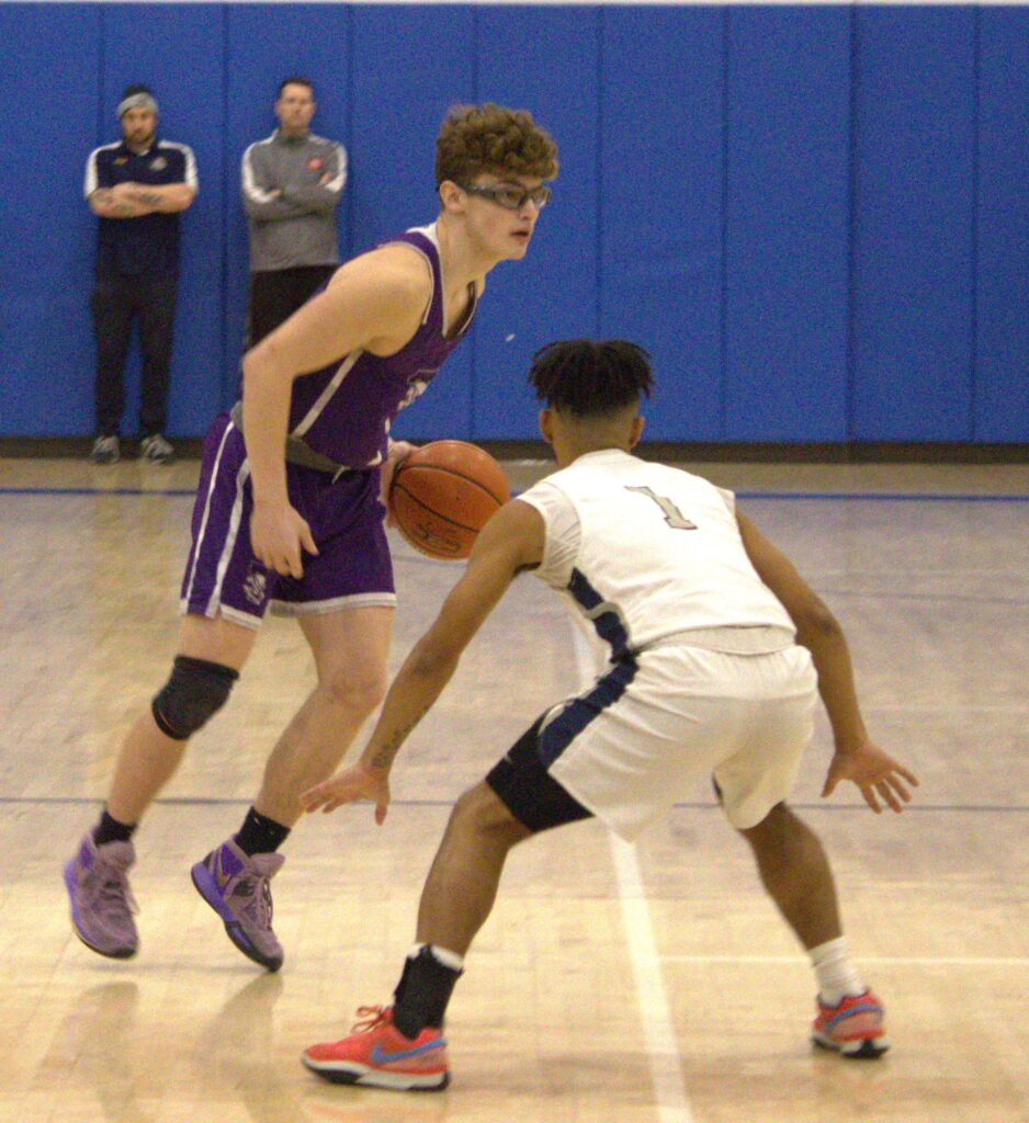 Two young men playing basketball on a court during the SIHSL Tournament championship.