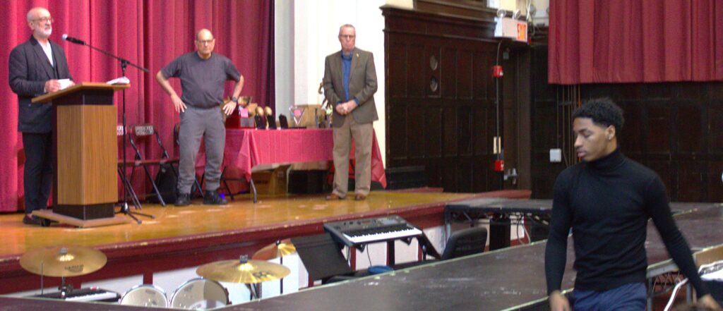 A man named Smith stands in front of a stage.