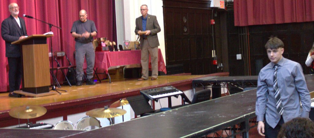 A man standing on a stage in front of a group of people, perhaps receiving an award.