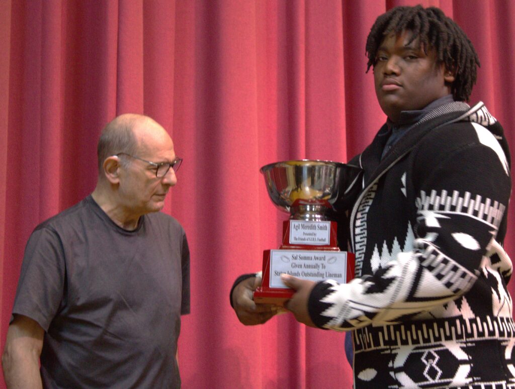 A man holding an award trophy.