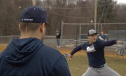 A baseball player is throwing a ball on a field at St. Joseph's University.