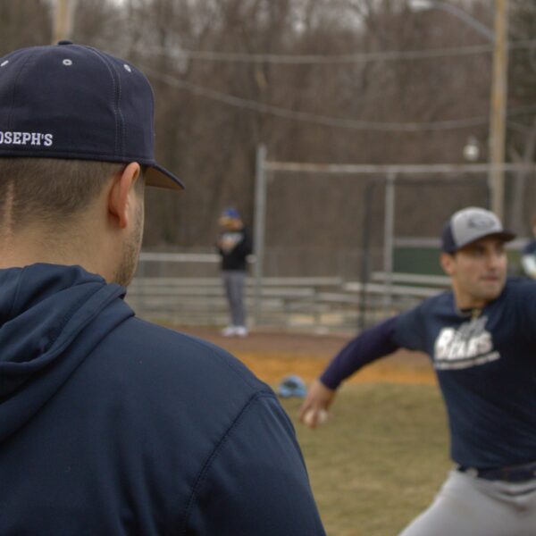 A baseball player is throwing a ball on a field at St. Joseph's University.