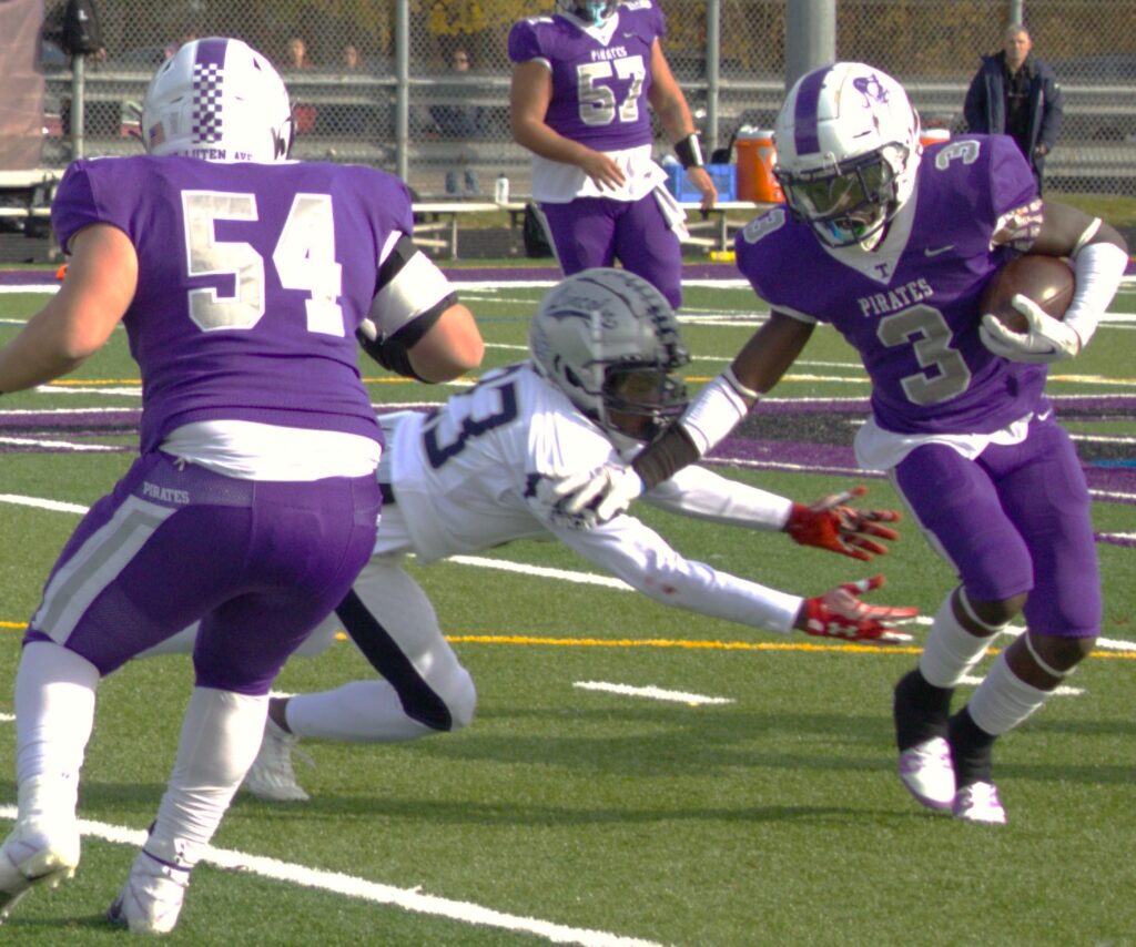 A high school football player is running on a field.