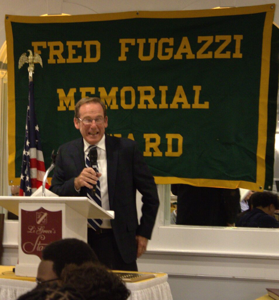 A man stands in front of a podium at Tottenville, Fred Fugazzi's alma mater.