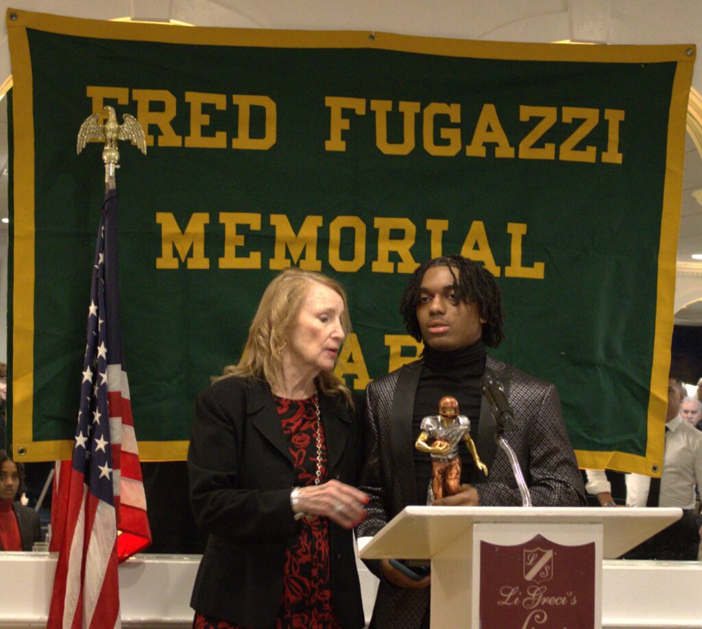 A man standing at a podium with a woman standing behind him in Tottenville.