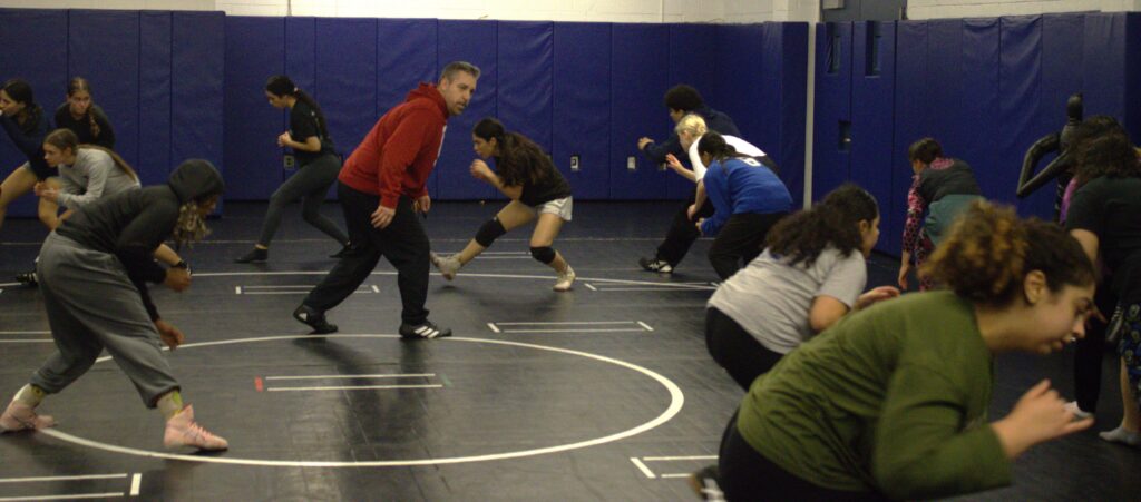 A group of PSAL island girls' wrestlers in a wrestling ring.