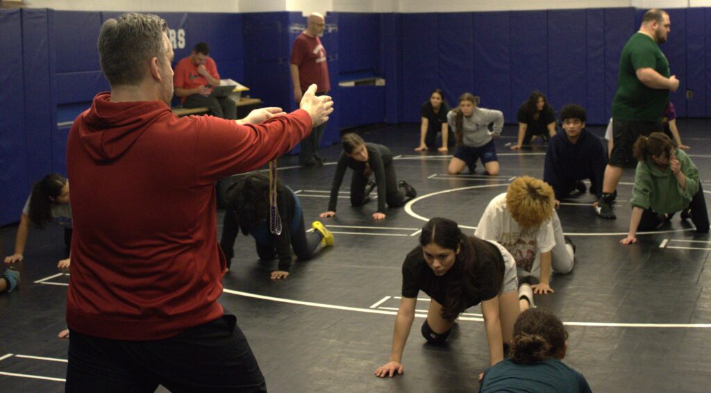 A group of PSAL Island girls' wrestlers practicing in a gym.