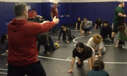 A group of PSAL Island girls' wrestlers practicing in a gym.