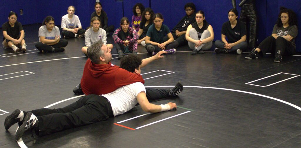 A group of PSAL island girls' wrestlers sitting on the floor.